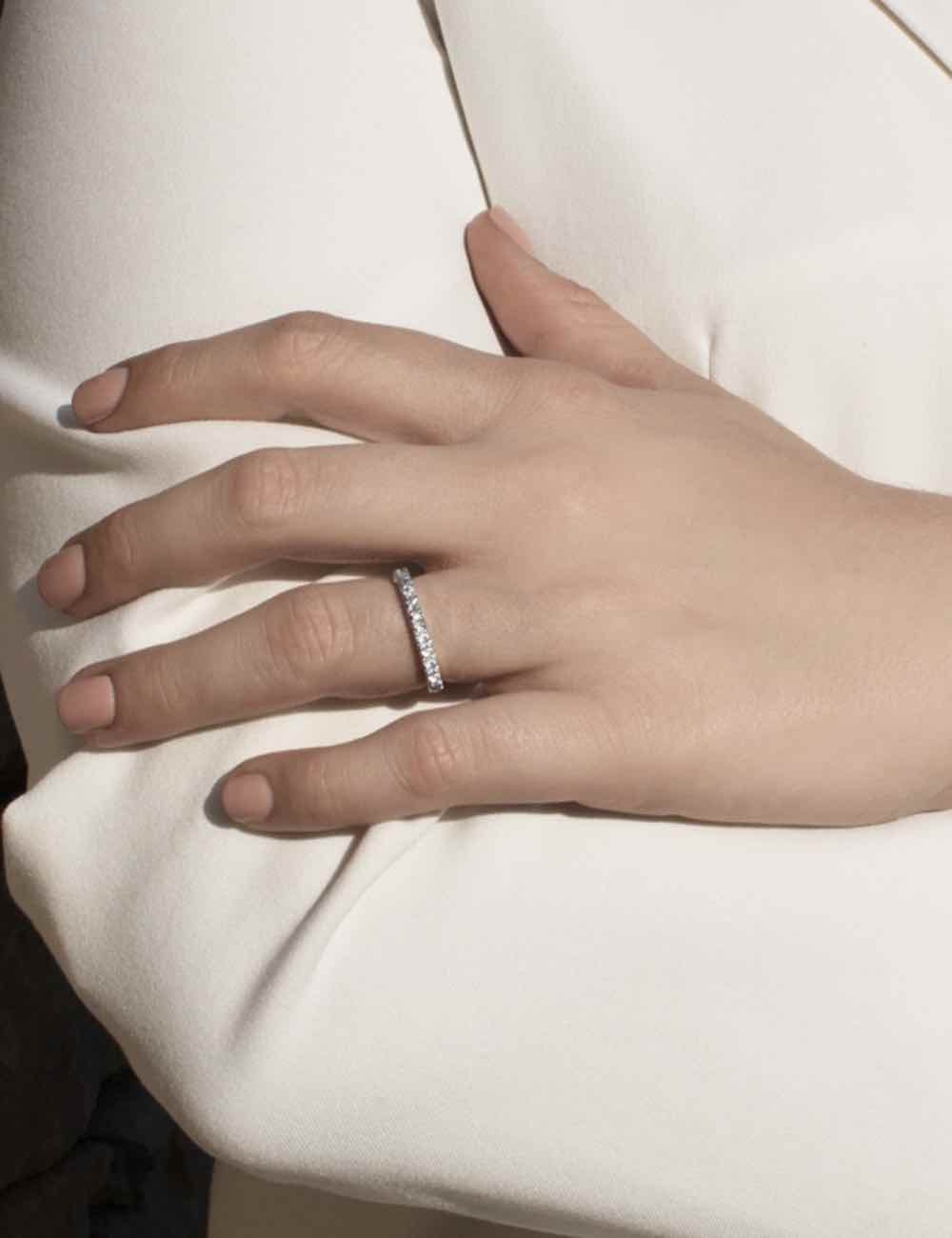 Women's platinum wedding band with white diamonds in a half-eternity setting, claw-set, creating a refined sparkle.