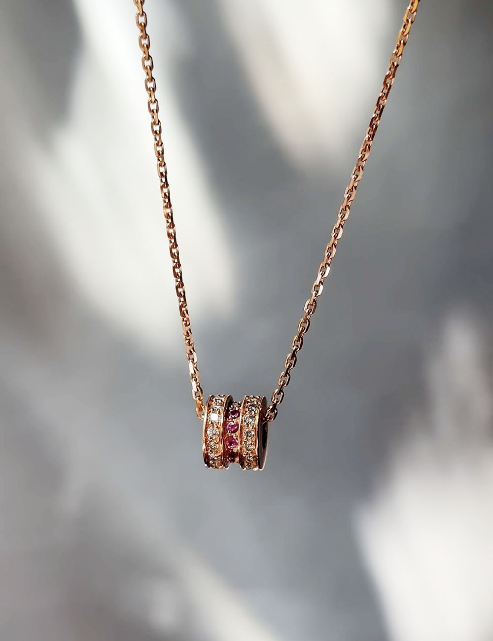 Rose gold pendant featuring white diamonds and pink sapphires in a refined, elegant design.