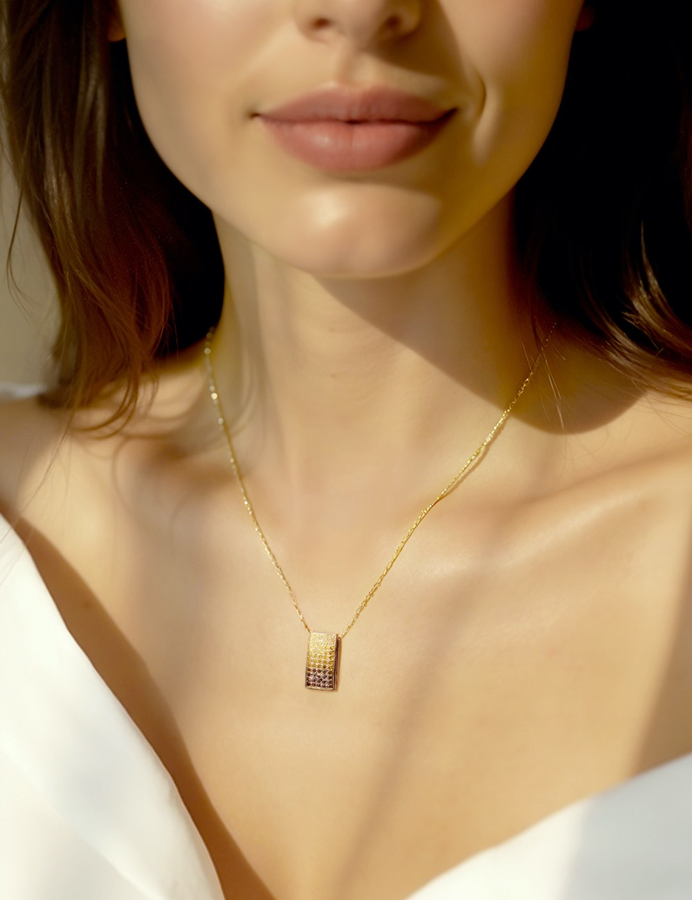 Femme portant un collier en or jaune avec un pendentif en diamants dégradés. Lumière chaude et élégance naturelle.