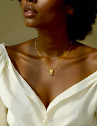 Woman wearing a yellow gold necklace with a gradient diamond pendant. Warm lighting and natural elegance